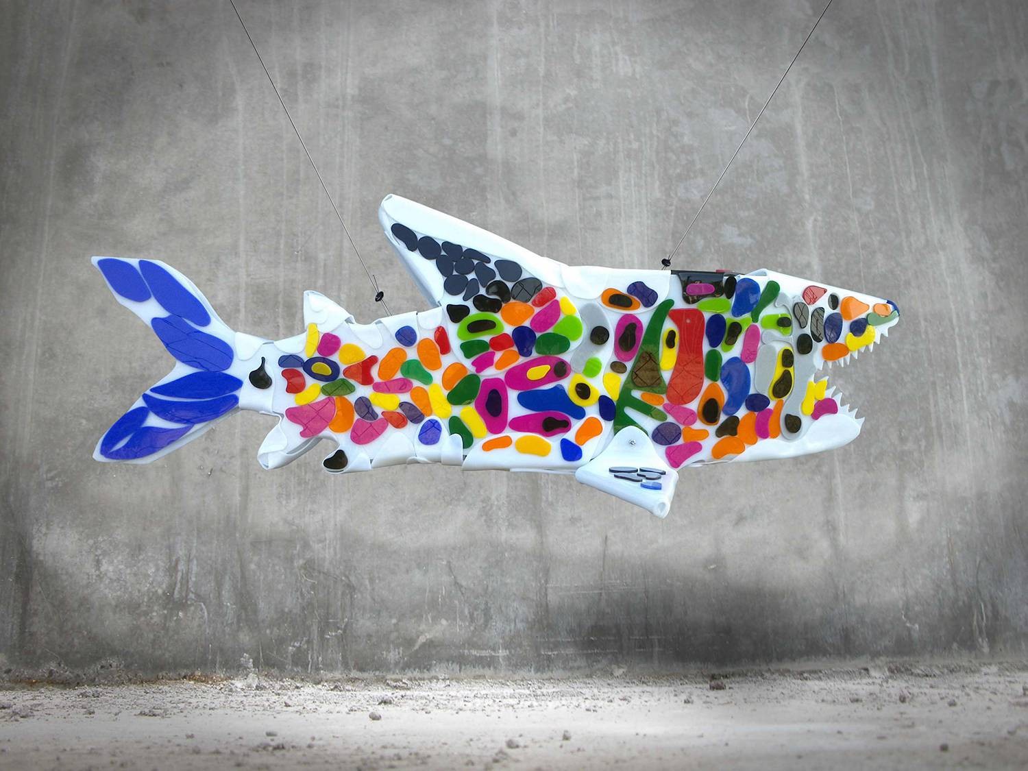 Colorized moments is a light shark sculpture on a concrete background.
